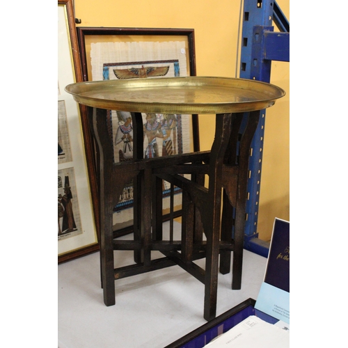 74 - A BRASS TOPPED FOLDING TABLE ON OAK LEGS