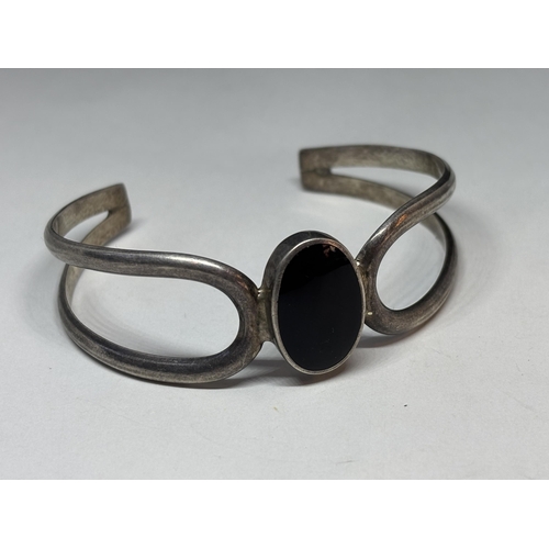 69 - A SILVER BANGLE WITH BLACK CENTRE STONE GROSS WEIGHT 26.8 GRAMS