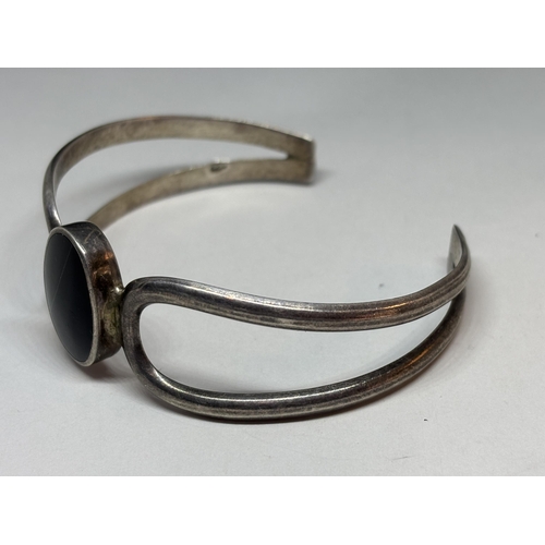 69 - A SILVER BANGLE WITH BLACK CENTRE STONE GROSS WEIGHT 26.8 GRAMS