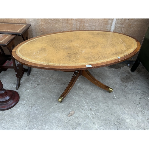 2996 - AN OVAL MAHOGANY COFFEE TABLE WITH INSET LEATHER TOP ON PEDESTAL BASE WITH BRASS CASTERS 48