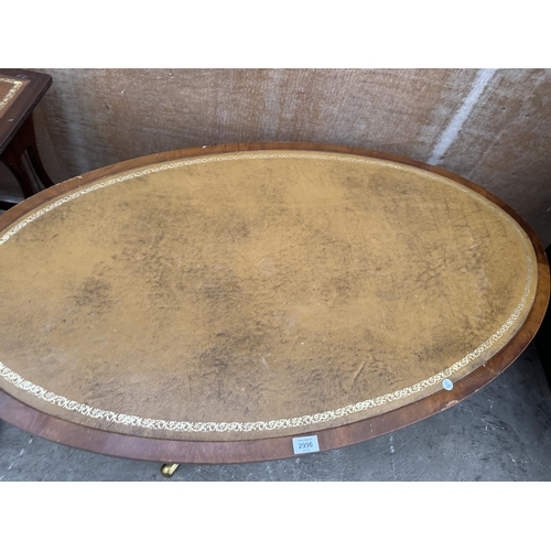 2996 - AN OVAL MAHOGANY COFFEE TABLE WITH INSET LEATHER TOP ON PEDESTAL BASE WITH BRASS CASTERS 48