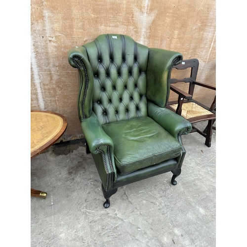 2997 - A GREEN LEATHER WINGED BUTTON BACK FIRESIDE CHAIR ON CABRIOLE LEGS