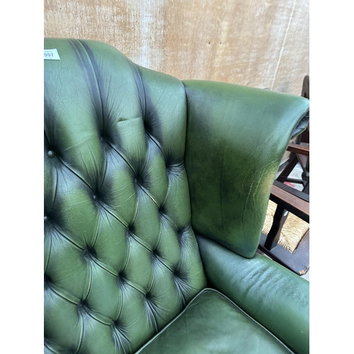 2997 - A GREEN LEATHER WINGED BUTTON BACK FIRESIDE CHAIR ON CABRIOLE LEGS