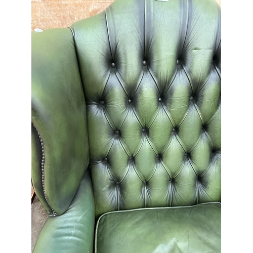 2997 - A GREEN LEATHER WINGED BUTTON BACK FIRESIDE CHAIR ON CABRIOLE LEGS