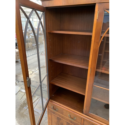 3070 - A YEW WOOD THREE DOOR GLAZED BOOKCASE ON BASE. 59