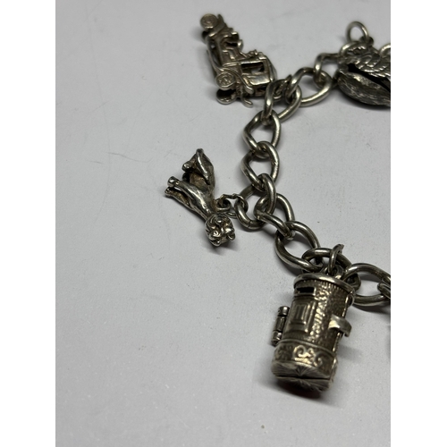 708 - A SILVER CHARM BRACELET WITH EIGHT CHARMS AND A HEART PADLOCK