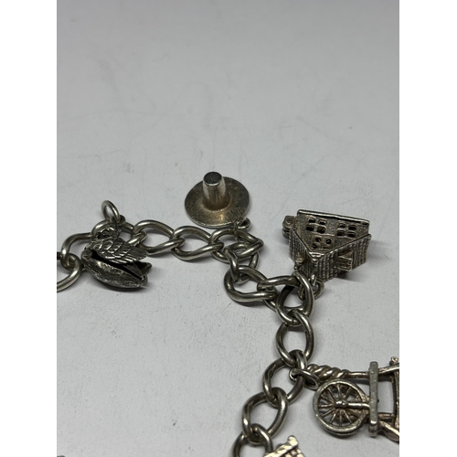 708 - A SILVER CHARM BRACELET WITH EIGHT CHARMS AND A HEART PADLOCK