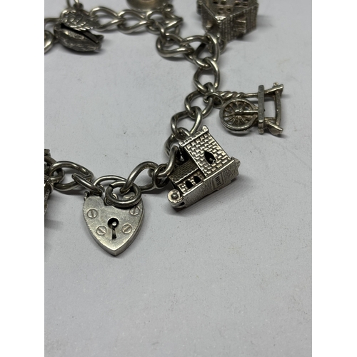 708 - A SILVER CHARM BRACELET WITH EIGHT CHARMS AND A HEART PADLOCK