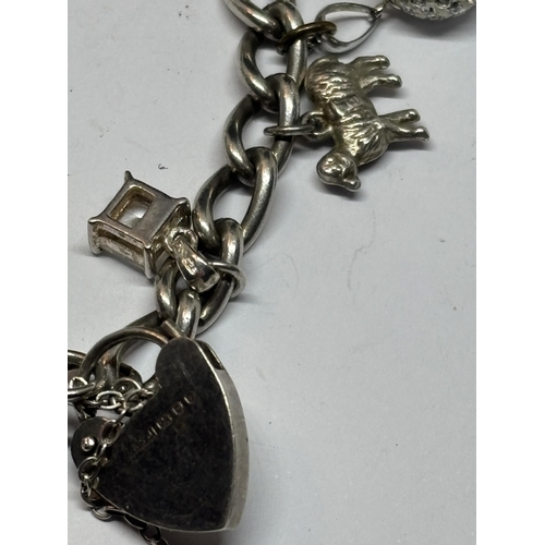 539 - A SILVER CHARM BRACELET WITH TEN CHARMS AND A HEART PADLOCK