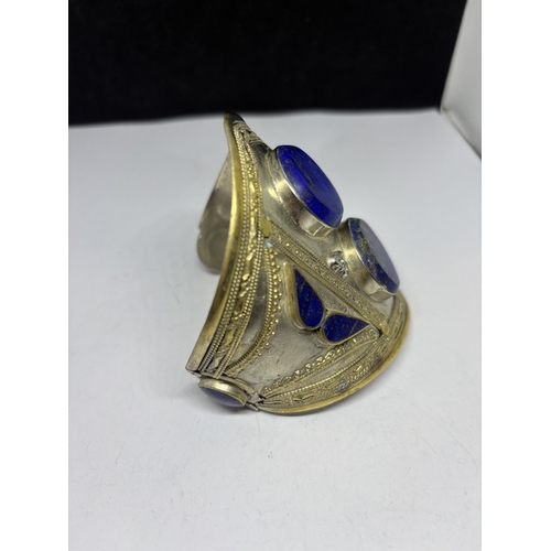 561 - AN ASIAN SILVER BANGLE WITH BLUE STONE DECORATION