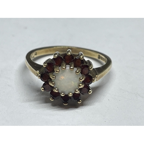 511 - A 9 CARAT YELLOW GOLD RING WITH CENTRE OPAL SURROUNDED BY GARNETS IN A FLOWER DESIGN SIZE M IN A PRE... 