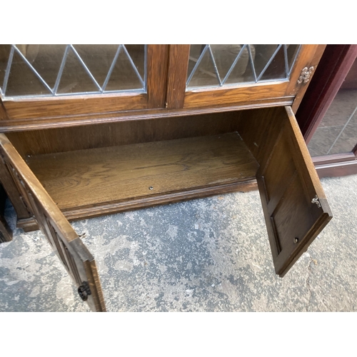 2747 - AN OAK GLAZED AND LEADED TWO DOOR BOOKCASE WITH LINEN FOLD DOORS TO BASE, 38