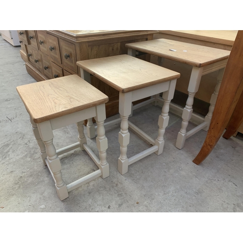 2533 - AN OAK NEST OF THREE TABLES ON PAINTED BASE WITH TURNED LEGS