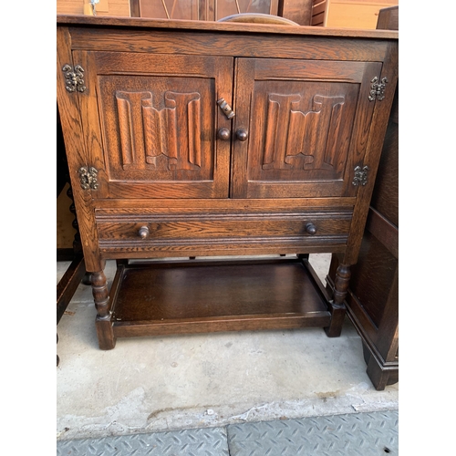 2588 - AN OAK JACOBEAN STYLE TWO DOOR CABINET WITH LINEN FOLD DOORS, SINGLE DRAWER ON OPEN BASE, 31