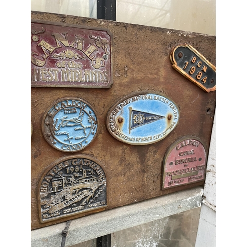 1513 - A WOODEN BOARD CONTAINING VARIOUS VINTAGE CAST FESTIVAL PLAQUES