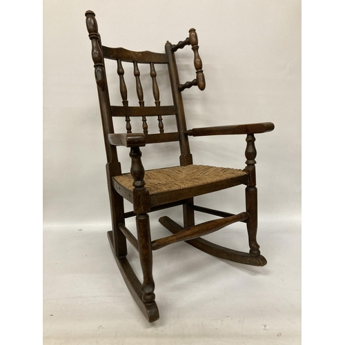 48 - AN 18TH CENTURY STYLE BEECH FRAMED CHILD'S ROCKING CHAIR WITH A RUSH SEAT