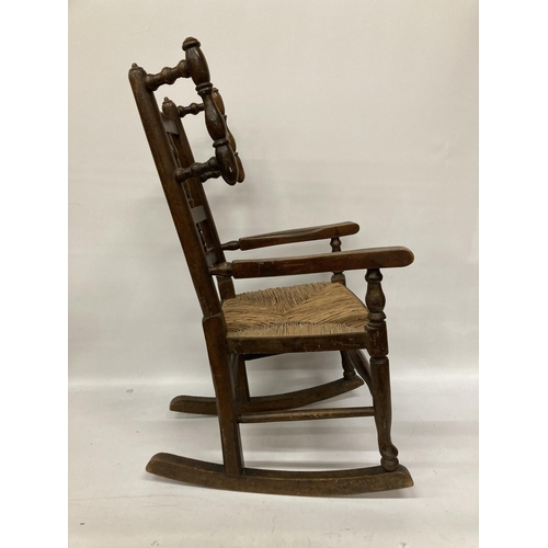 48 - AN 18TH CENTURY STYLE BEECH FRAMED CHILD'S ROCKING CHAIR WITH A RUSH SEAT