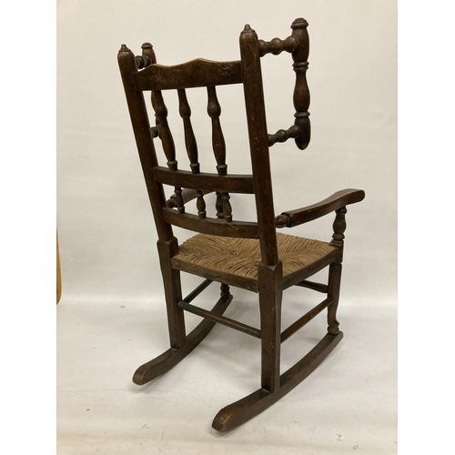 48 - AN 18TH CENTURY STYLE BEECH FRAMED CHILD'S ROCKING CHAIR WITH A RUSH SEAT