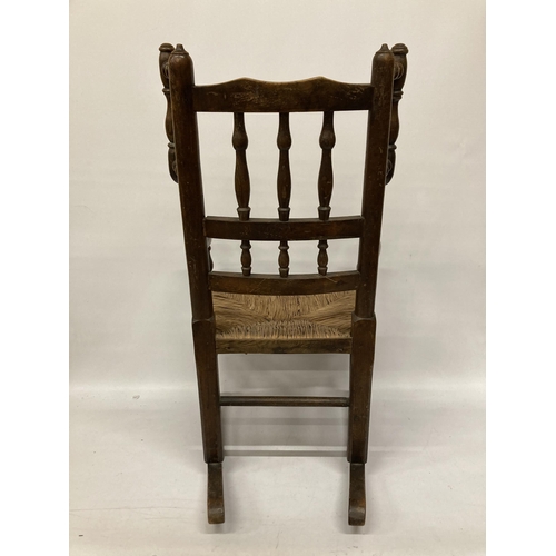 48 - AN 18TH CENTURY STYLE BEECH FRAMED CHILD'S ROCKING CHAIR WITH A RUSH SEAT