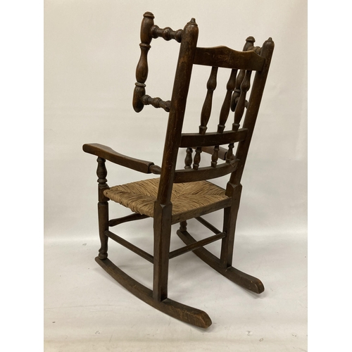 48 - AN 18TH CENTURY STYLE BEECH FRAMED CHILD'S ROCKING CHAIR WITH A RUSH SEAT