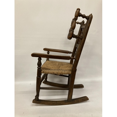 48 - AN 18TH CENTURY STYLE BEECH FRAMED CHILD'S ROCKING CHAIR WITH A RUSH SEAT