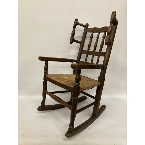 48 - AN 18TH CENTURY STYLE BEECH FRAMED CHILD'S ROCKING CHAIR WITH A RUSH SEAT