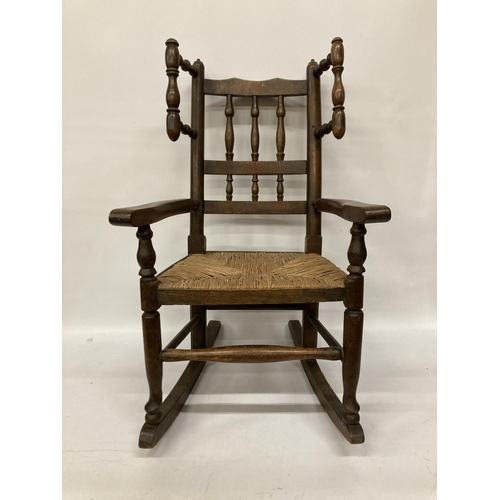 48 - AN 18TH CENTURY STYLE BEECH FRAMED CHILD'S ROCKING CHAIR WITH A RUSH SEAT