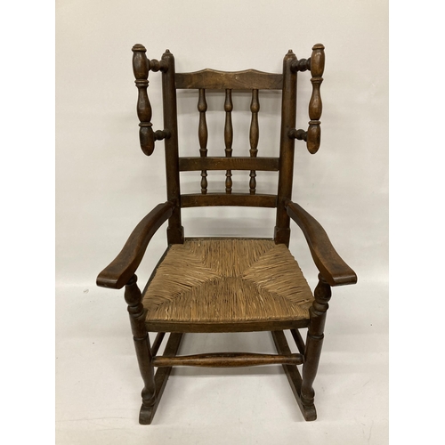 48 - AN 18TH CENTURY STYLE BEECH FRAMED CHILD'S ROCKING CHAIR WITH A RUSH SEAT