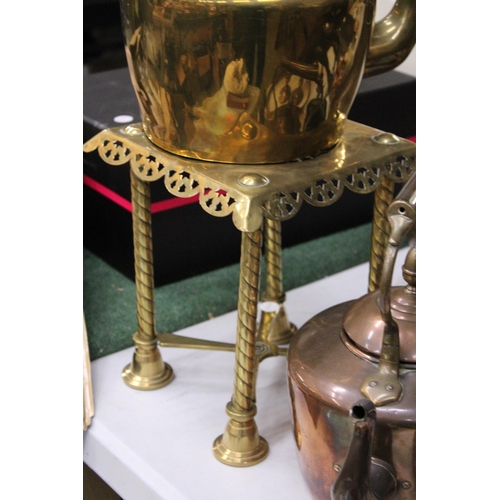 950 - A LARGE BRASS KETTLE ON A TRIVET PLUS A LARGE COPPER KETTLE BOTH WITH ACORN FINIALS