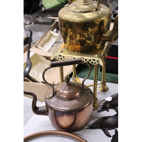 950 - A LARGE BRASS KETTLE ON A TRIVET PLUS A LARGE COPPER KETTLE BOTH WITH ACORN FINIALS