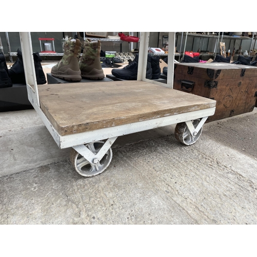 1797 - AN INDUSTRIAL STYLE SHELVING UNIT WITH PLANK SHELVES AND RAILWAY TROLLEY WHEEL BASE