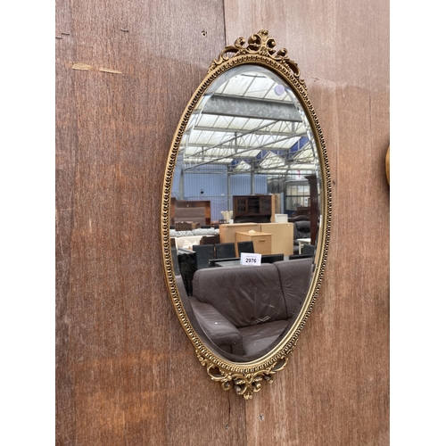 2976 - AN OVAL GILT FRAMED BEVEL EDGE WALL MIRROR WITH FOLIATE FRAME, 26