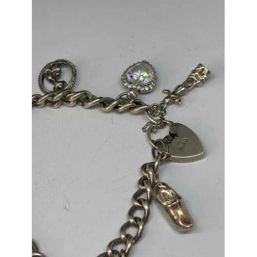 523 - A MARKED SILVER CHARM BRACELET WITH TEN CHARMS AND A HEART PADLOCK