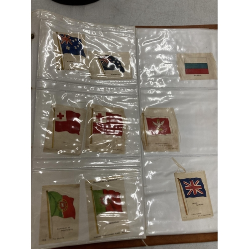 245 - A COLLECTION OF VINTAGE SILK FLAGS IN AN ALBUM