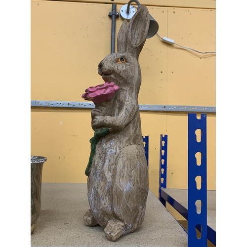 412 - A WOODEN MODEL OF A RABBIT HOLDING A FLOWER, HEIGHT 46CM