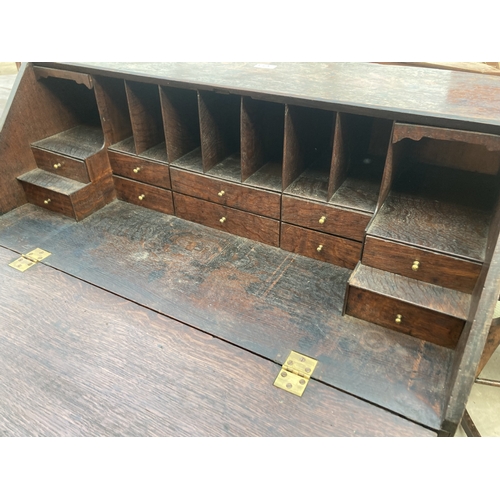 3169 - A GEORGE III OAK BUREAU WITH FITTED INTERIOR AND SEVEN DRAWERS TO BASE ON BRACKET FEET 36