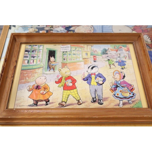 424 - A COLLECTION OF RUPERT THE BEAR ITEMS TO INCLUDE CUPS, A CERAMIC WALL CLOCK, EGG CUPS, TWO FRAMED JI... 