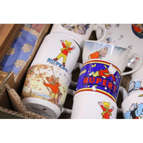 424 - A COLLECTION OF RUPERT THE BEAR ITEMS TO INCLUDE CUPS, A CERAMIC WALL CLOCK, EGG CUPS, TWO FRAMED JI... 