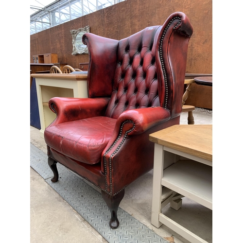 2606 - AN OXBLOOD CHESTERFIELD STYLE WINGED ARMCHAIR ON FRONT CABRIOLE LEGS