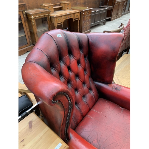 2606 - AN OXBLOOD CHESTERFIELD STYLE WINGED ARMCHAIR ON FRONT CABRIOLE LEGS