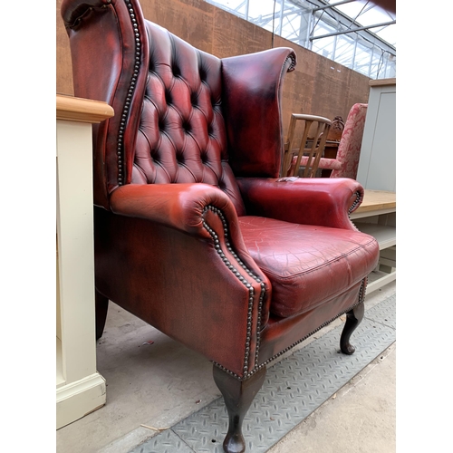 2606 - AN OXBLOOD CHESTERFIELD STYLE WINGED ARMCHAIR ON FRONT CABRIOLE LEGS