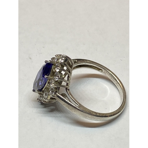 551 - A MARKED SILVER DRESS RING WITH AN AMETHYST COLOURED STONE SURROUNDED BY CLEAR STONES IN A PRESENTAT... 