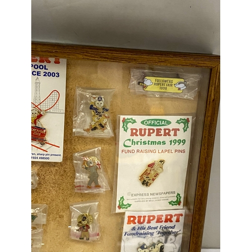 24 - A COLLECTION OF VINTAGE RUPERT THE BEAR BADGES IN A GLASS CASE