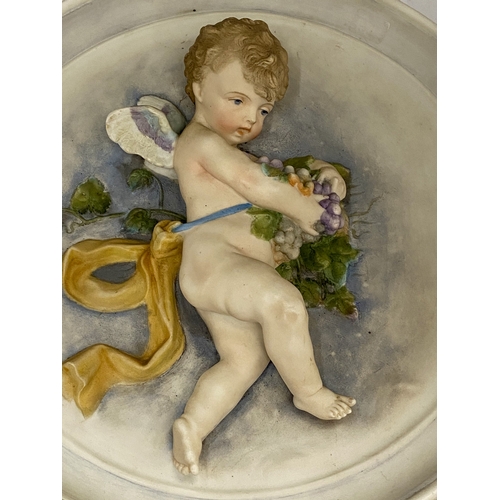 28 - A FINE ANTIQUE BISQUE POLYCHROME PORCELAIN WALL PLAQUE OF A CHERUB HOLDING GRAPES IN THE STYLE OF BA... 
