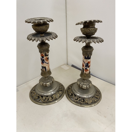 7 - A PAIR OF CANDLESTICKS WITH INTRICATE SCROLLWORK DETAIL WITH A DECORATIVE CERAMIC CENTRAL COLUMN