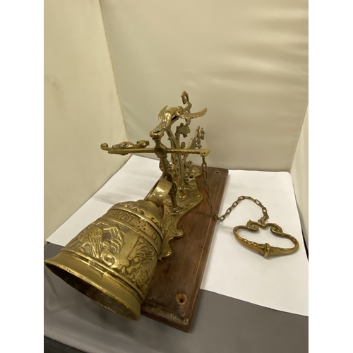 26 - A VINTAGE BRASS BELL ON AN ORNATE BRACKET AND WOODEN PLINTH