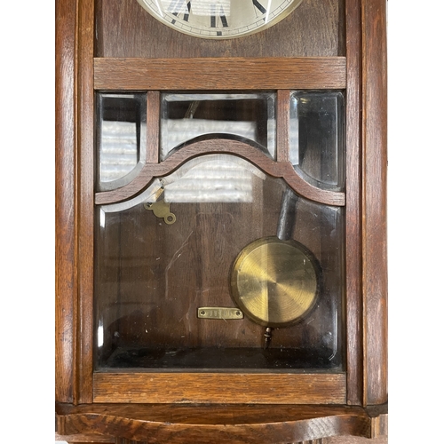 21 - A WESTMINSTER CHIMING OAK CASED WALL CLOCK WITH PENDULUM AND KEY