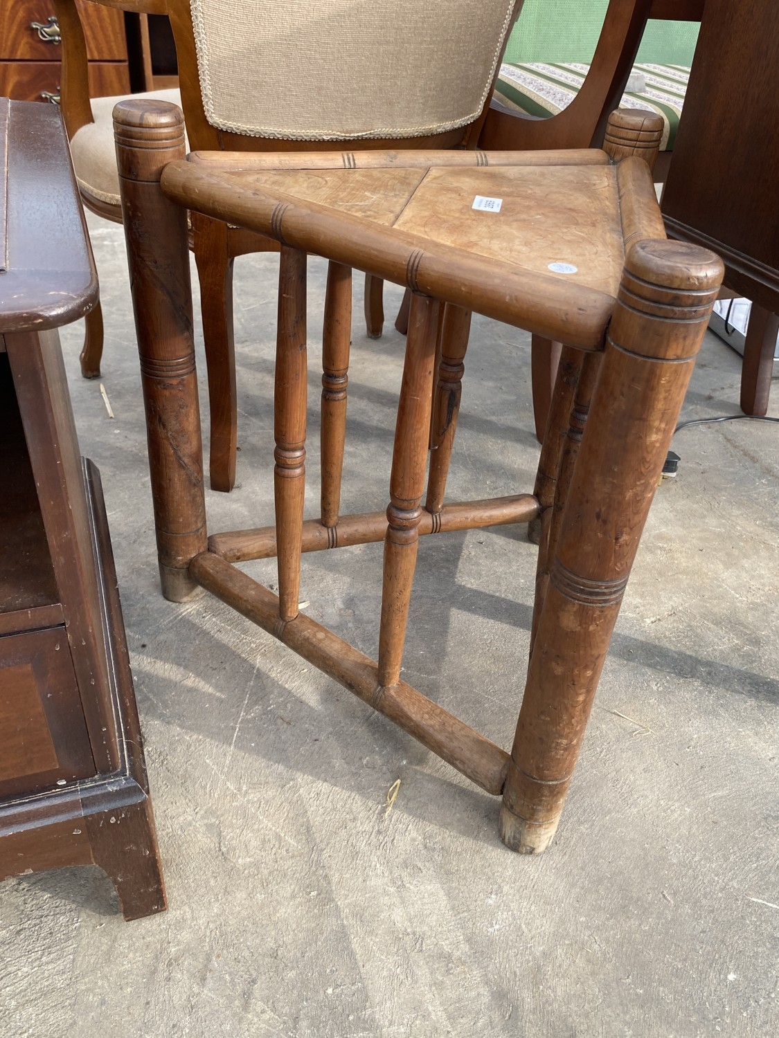 A THREE FOOTED TRIANGULAR SHAPED STOOL ON TURNED LEGS