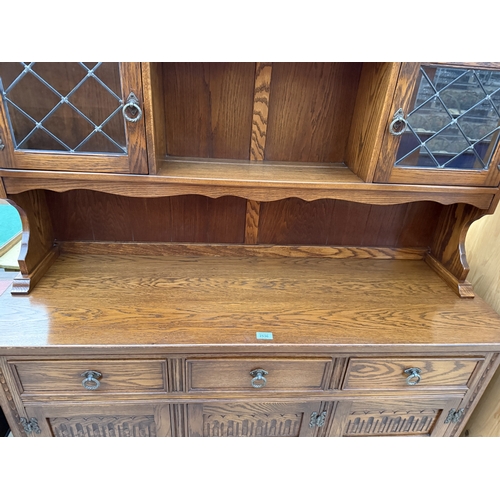 2536 - A JAYCEE OAK DRESSER WITH RACK ENCLOSING TWO GLAZED AND LEADED DOORS, 54