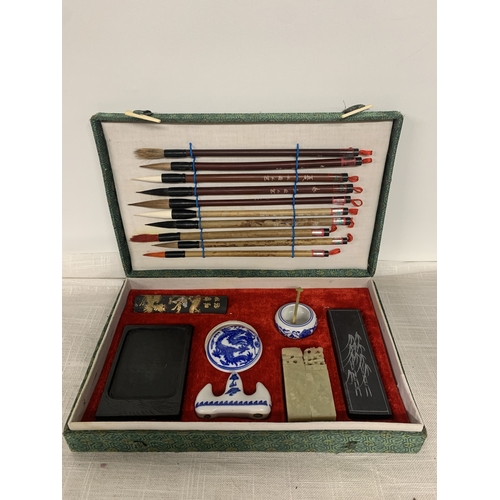 312 - A VINTAGE CHINESE CALLIGRAPHY SET TO INCLUDE A VARIETY OF BRUSHES, INK STONE, PORCELAIN WATER POT ET... 